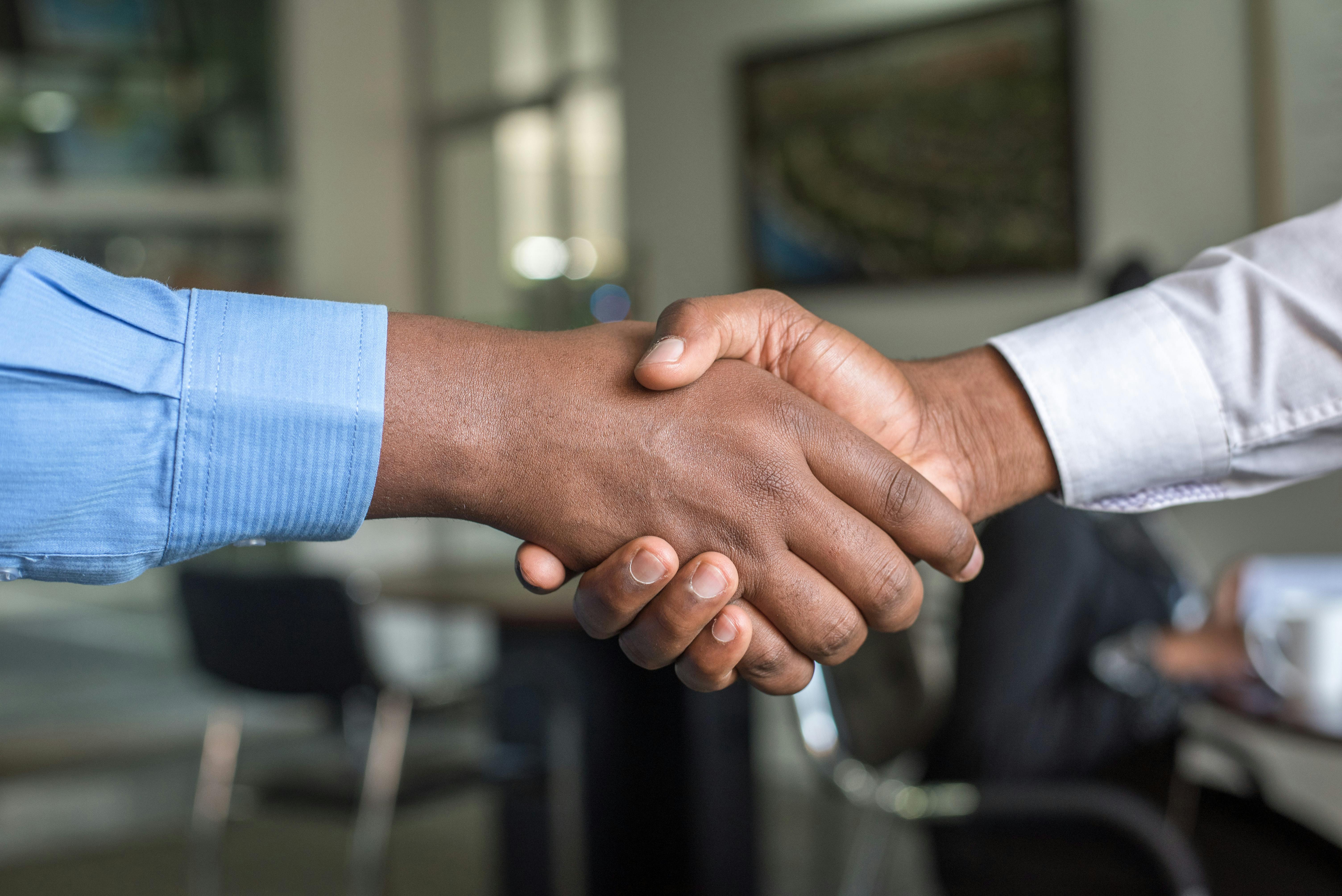 two people in dress shirts shaking hands
