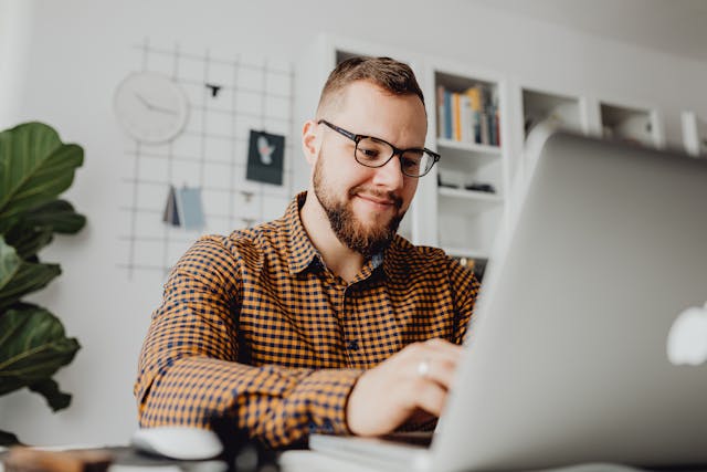 A man sitting at a desk, using a laptop.