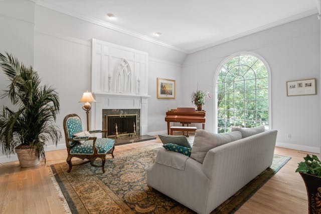 Open seating area with a couch and a chair, a piano in the corner and neutral decor