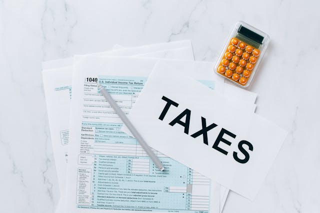 a page that reads TAXES overtop 1040 forms and next to a calculator with orange buttons